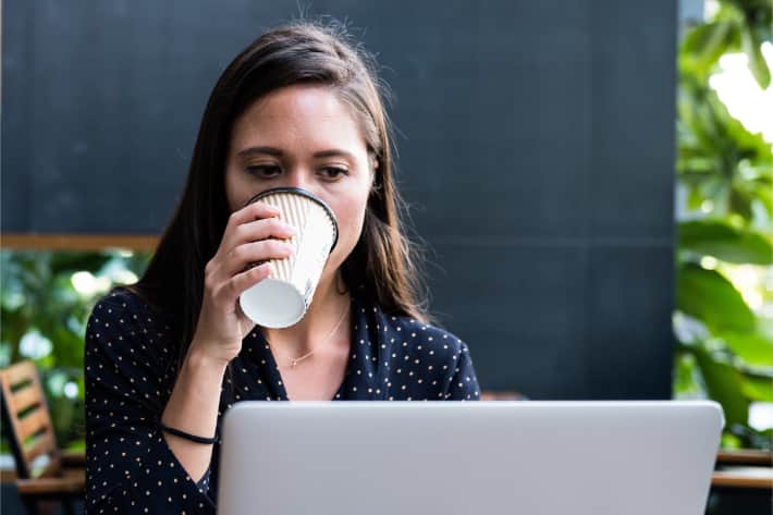 Woman browsing on laptop and sipping coffee Woman browsing on laptop and sipping coffee